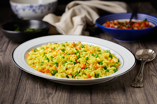Fresh hot fried rice on a dark background with chopsticks and plates