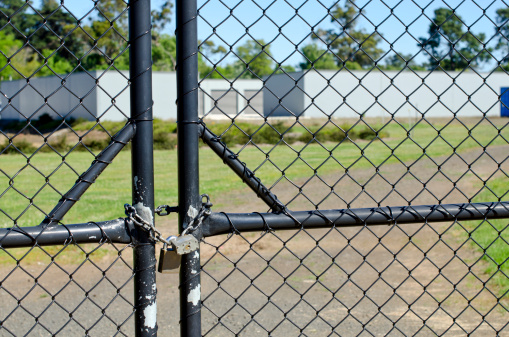 Locked gate with wire mesh securing warehouses