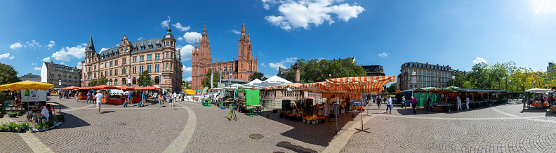 Wiesbaden, Germany - September 4, 2021: people enjoy the farmers market downtown Wiesbaden at square Dernsches Gelände in Wiesbaden with historic market church and town hall.