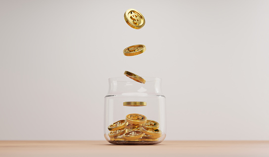 Golden coin dropping to transparent saving jar on wooden table for investment and banking financial saving deposit concept by 3d rendering.
