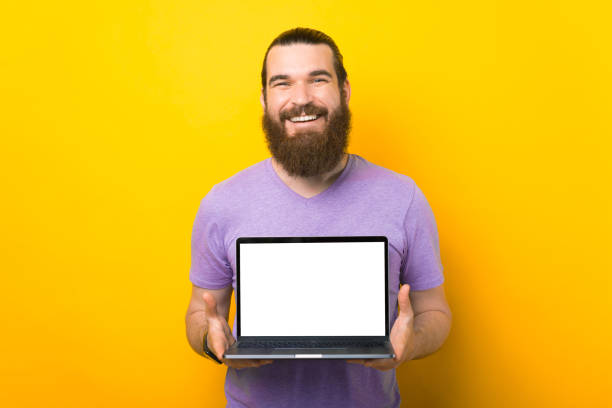 素晴らしいひげを生やした男は、カメラに空白のスクリーンラップトップを保持しています。 - laptop men computer home interior ストックフォトと画像