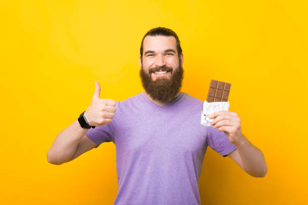 istock Happy bearded man is showing like gesture and a whole chocolate bar. 1339425510