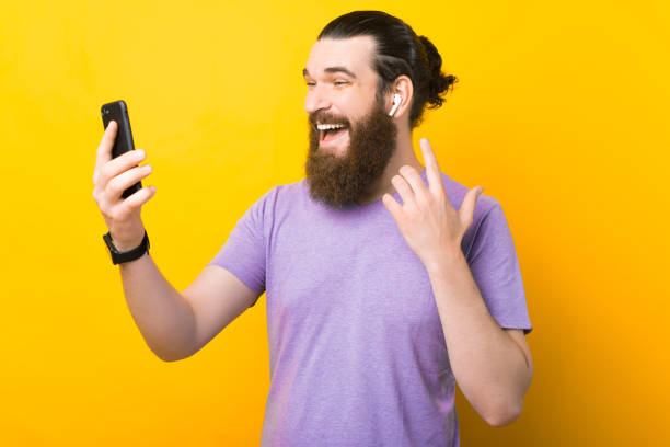 istock Excited bearded man is using his earphones and phone. 1339425535