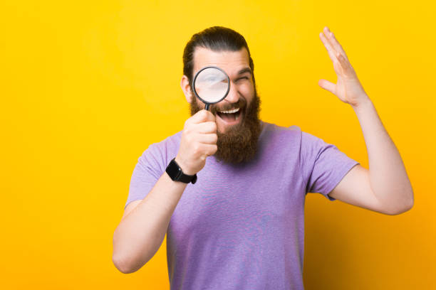 istock Excited bearded man is looking through magnifying glass at the camera. 1339425545