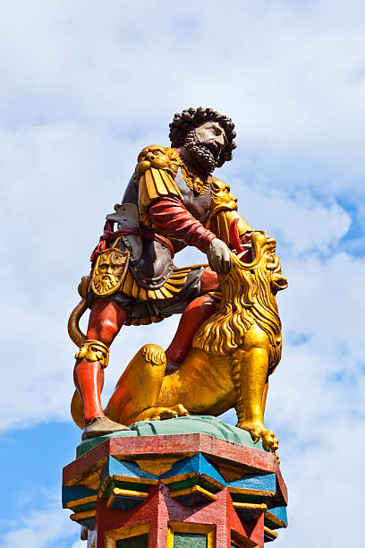 Beautiful City Street View of the colorful medieval Messenger statue on top of elaborate fountain in Bern, Switzerland. The fountain is attributed to Hans Gieng in 16th century.
