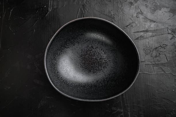 istock black pottery bowl, with copy space for text or food, with copy space for text or food, top view flat lay , on black dark stone table background 1339432122
