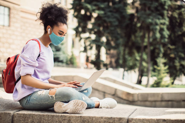 istock Black Student Girl Using Laptop Wearing Face Mask Outside, Side-View 1339432702