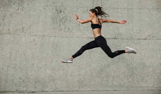 Photo of Female athlete running and jumping outdoors