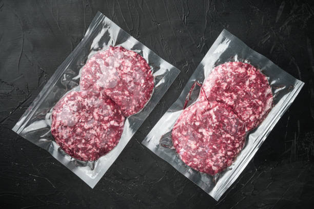 Beef patties in a vacuum packing, on black stone background, top view flat lay Beef patties in a vacuum packing set, on black stone background, top view flat lay vacuum packed stock pictures, royalty-free photos & images
