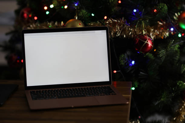 istock Laptop with blank white screen on behind is Christmas tree with garland 1339436840