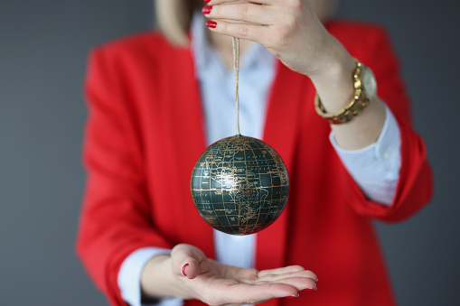 Woman in a business suit holds ball with world map. World politics and diplomacy concept
