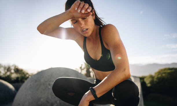 уставшая женщина сидит и отдыхает после тренировки - women sweat healthy lifestyle exercising стоковые фото и изображения