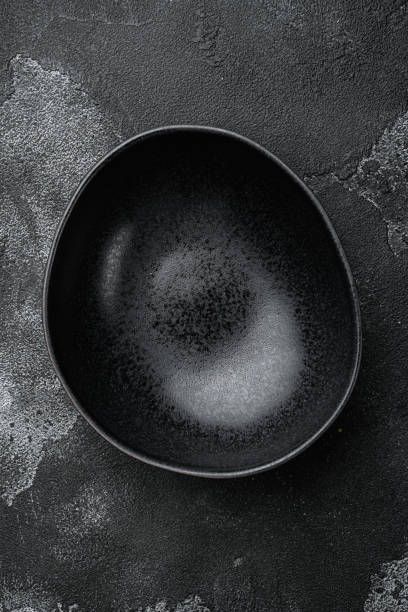 istock Black bowl, with copy space for text or food, with copy space for text or food, top view flat lay , on black dark stone table background 1339436933