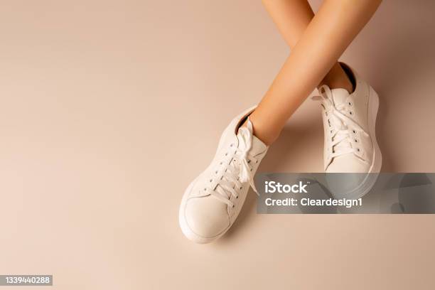 White Sneakers Shoes And Girlâs Legs On Nude Background Casual Footwear Stock Photo - Download Image Now