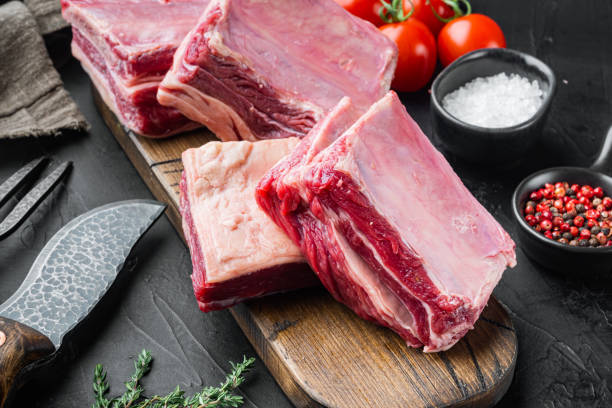 istock Raw meat ribs, with ingredients , on black stone background 1339443177