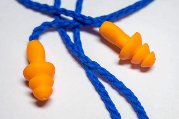 istock New orange earplugs with blue rope on a white table. 1339444227