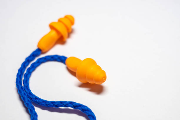 istock Close-up new orange earplugs with blue rope on a white table. 1339444236