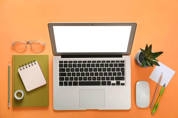 istock Laptop and office stationery on orange background, flat lay 1339445263