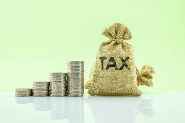 istock Tax bag, 4 rows of increasing coins on a table 1339445625