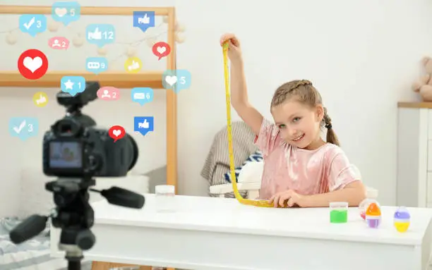 Photo of Cute little blogger with slime recording video at home