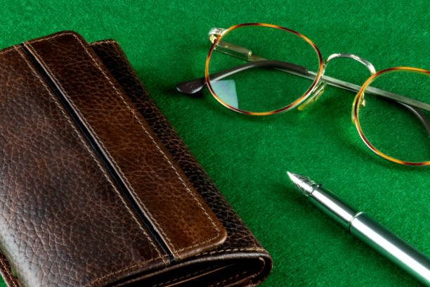 Spectacles fountain pen and leather wallet on a felt covered table
