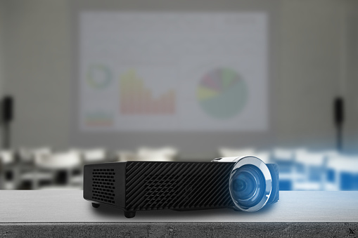 Modern video projector and blurred conference room on background
