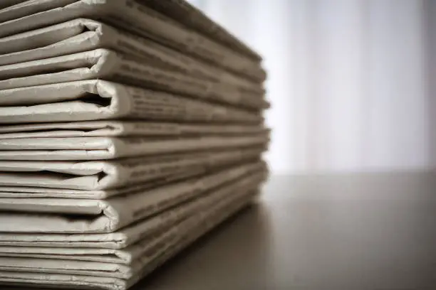 Photo of Stack of newspapers on grey table, space for design. Journalist's work