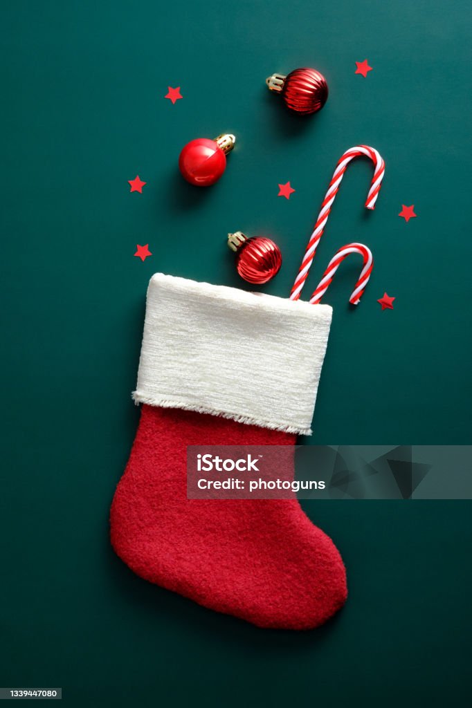 Vintage Santa stocking with candy canes, red balls, and decorations on green background Christmas Stocking Stock Photo