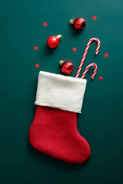 Photo of Vintage Santa stocking with candy canes, red balls, and decorations on green background