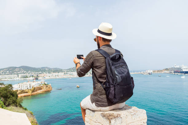 Young  man sitting at sea view point with backpack. stock photo