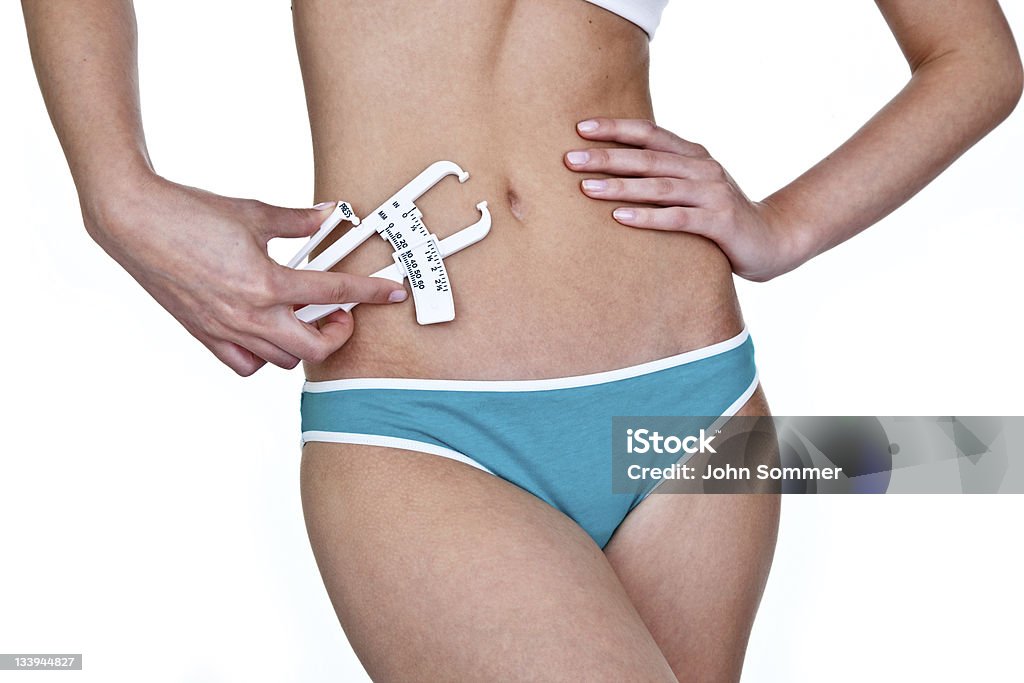 Mujer tomando una medición de la grasa corporal - Foto de stock de 20 a 29 años libre de derechos