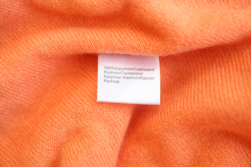 orange, soft, cashmere closeup with tag 100% cashmere