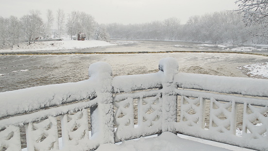 Snow covered wooden railing in winter day, Kuldiga, Latvia.