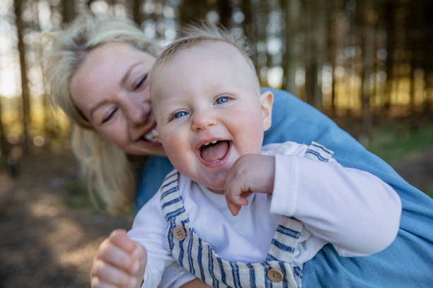 My Blue Eyed Boy A close-up of a woman holding her baby boy while standing in a woodland area, he is looking at the camera while she looks at him in awe. baby teeth stock pictures, royalty-free photos & images