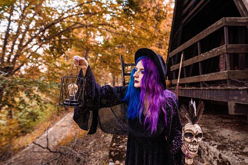 Young witch in front of her house in a forest.