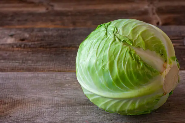 Fresh and raw head of cabbage isolated on rustic wooden table. Closeup view