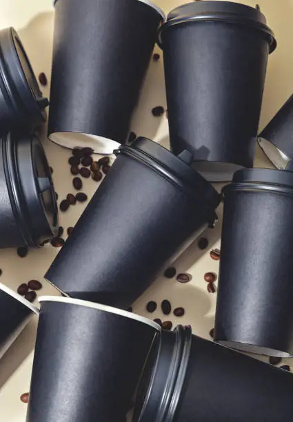Black paper cups for coffee and tea lie in a pile. View from above