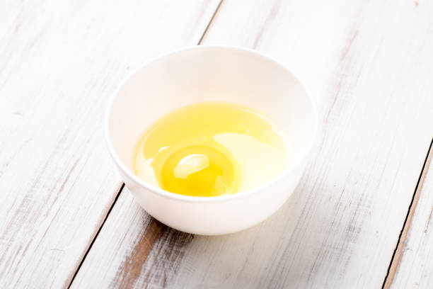 istock Raw egg in a plate on a white wooden background. 1339467481
