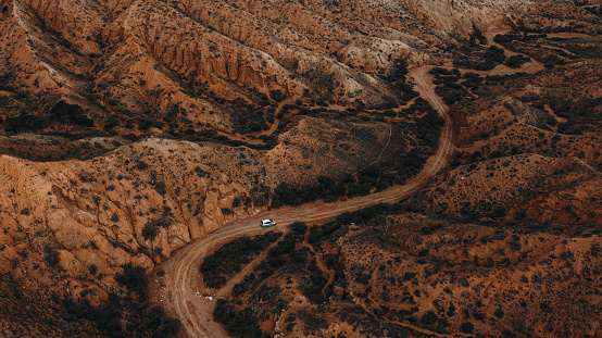 Drone photo of a car driving through the dramatic mountain colourful canyon near Issyk-Kul lake, Central Asia