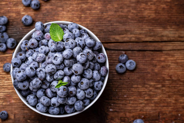 istock Fresh blueberries in a bowl on a brown wooden background. 1339467883