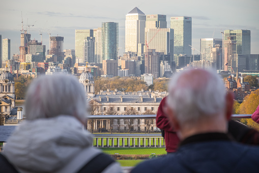 London, UK - 6 September, 2021 - Canary Wharf cityscape seen through a senior couple from the viewpoint on Greenwich hill