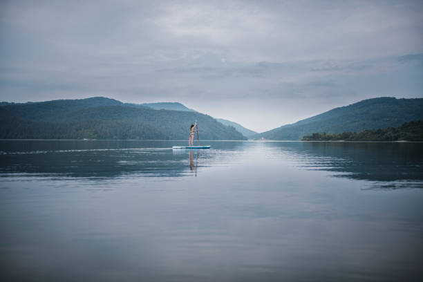 Full Length Of Woman Paddleboarding In Mountain lake