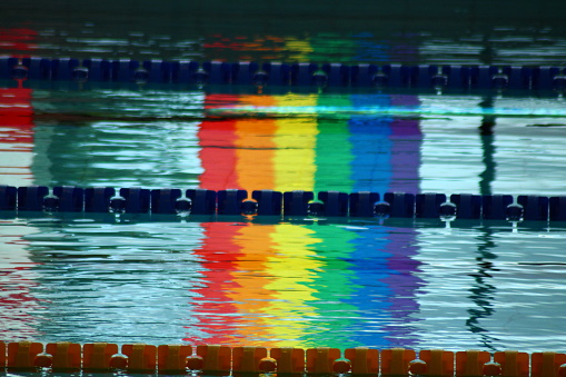 Reflection of LGBT symbols in a swimming pool. The swimming pool becomes gayly colored