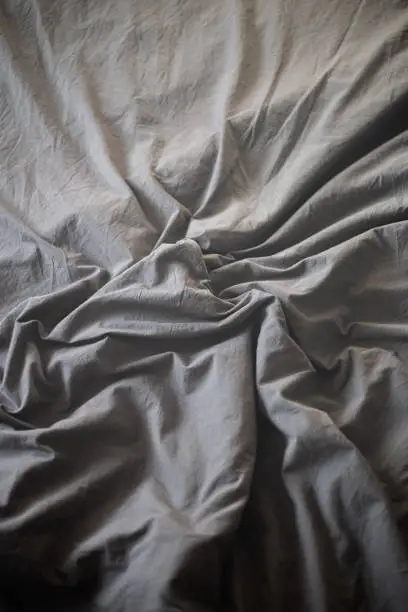 Black sheet crumpled and twisted on the bed