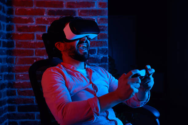 istock Excited man smiling while playing games in VR glasses, sitting on chair 1339476537