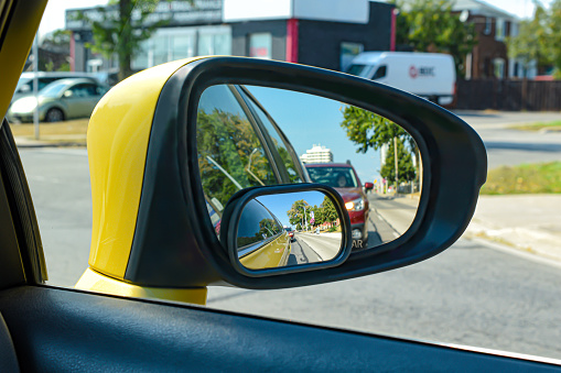 The view from a motor vehicle side mirror through the window. The image layers up due to the blind spot mirror giving a different angle of view.