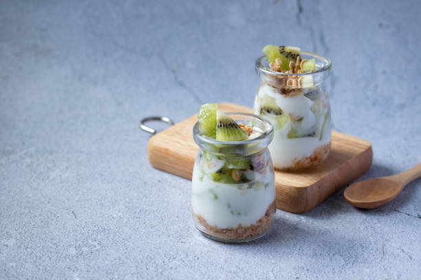istock Kiwi yogurt in a glass jar on a gray background. 1339478507
