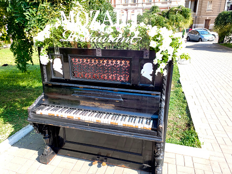 Odessa, Ukraine - August 23, 2021: The old part of Odessa city. The old piano with summer flowers on it.