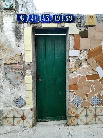 green wooden old door with many blue ceramic house numbers, in Sicily, Italy