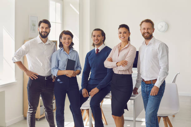 istock Group of young smiling business people looking at camera after successful project discussion 1339482642